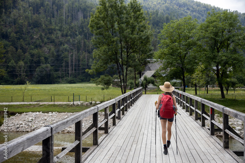 Mid Adult Woman Hiker Crossing Bridge over Bohinjska Bistrica River in Slovenia with a Backpack