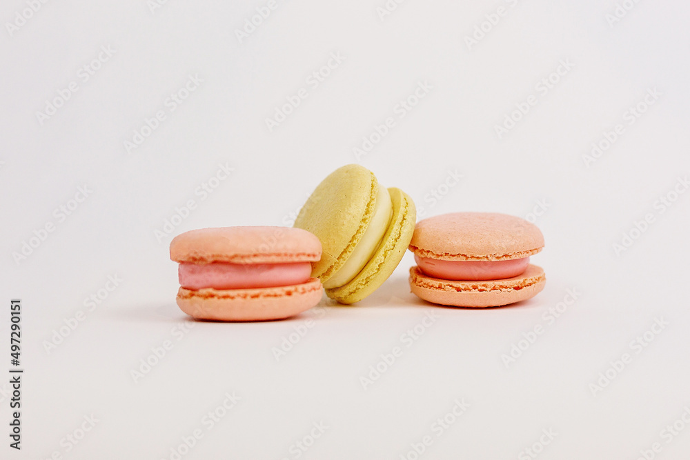 Multicolored macaroons on a solid white background with a place for writing and cutting. Minimalism. Yellow, orange, even. Beautiful cakes. Postcard. Multicolored macaroons on a solid white background with a place for writing and cutting. Minimalism. Yellow, orange, even. Beautiful cakes. Postcard.