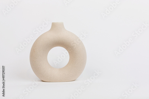 Beige vase of a beautiful flat round shape on a plain white background. The concept of Minimalism.