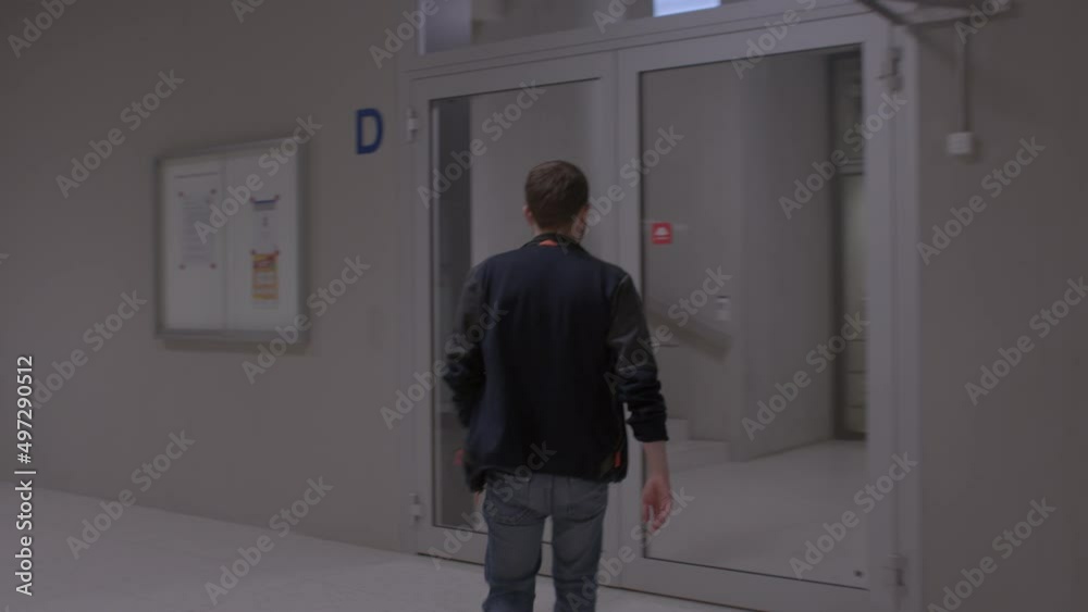 The back of the man exits the elevator, takes steps, opens the door, continues to move. Building movement. CH, Zurich, Otto-Stern-Weg, 11.3.22 The back of the man exits the elevator, takes steps, opens the door, continues to move. Building movement. CH, Zurich, Otto-Stern-Weg, 11.3.22