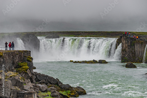 Scenic panoramic view of popular tourist attraction waterfall Godafoss in Iceland with tourists watching the sightseeing  summer  dramatic sky.