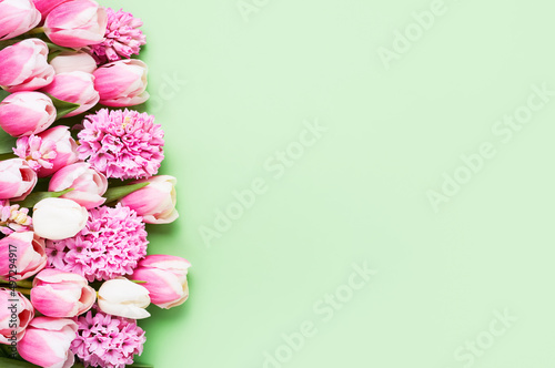 Border of pink hyacinths and tulips on green backdrop. Mothers Day, Valentines Day, birthday concept © Laima Gri