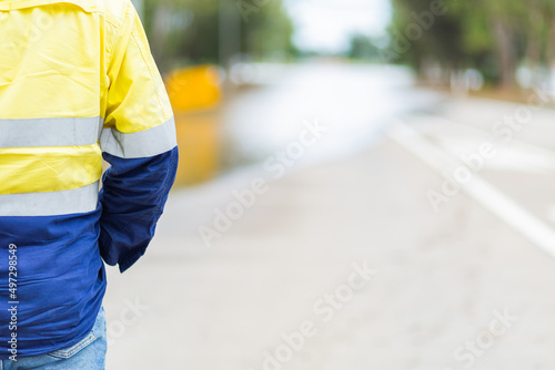 Council worker in high vis with copy space and floodwater over road photo