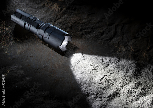 Survival flashlight that is illuminated and glowing on a rock in low light around photo