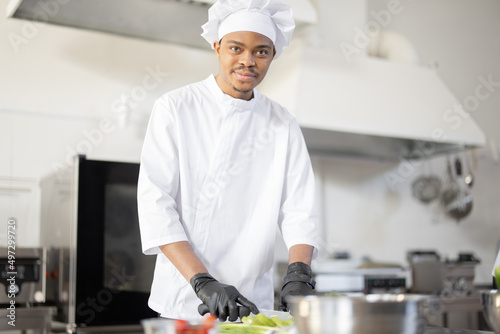 Portrait of young Latin-American chef cook in uniform cooking in the professional kitchen. Handsome guy working as cook at restaurant