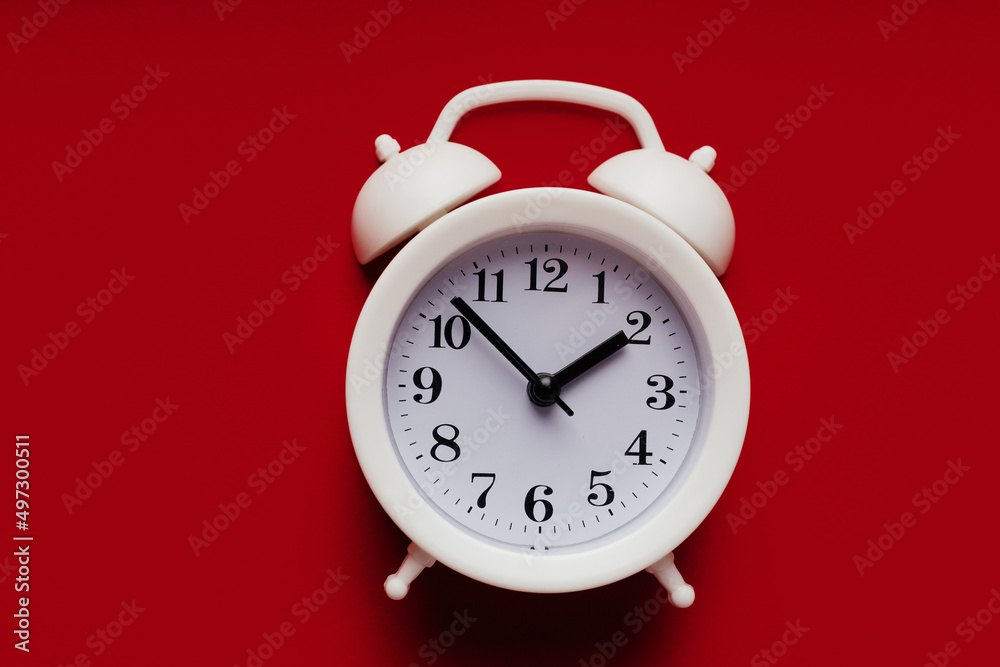 White alarm clock on a red background close-up White alarm clock on a red background close-up
