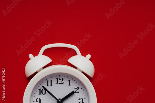 Part of white alarm clock on a red background. Deadline, reminder or concept of moment