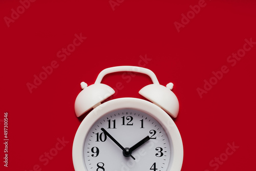 Part of white alarm clock on a red background close-up with copy space. Deadline, reminder or concept of moment