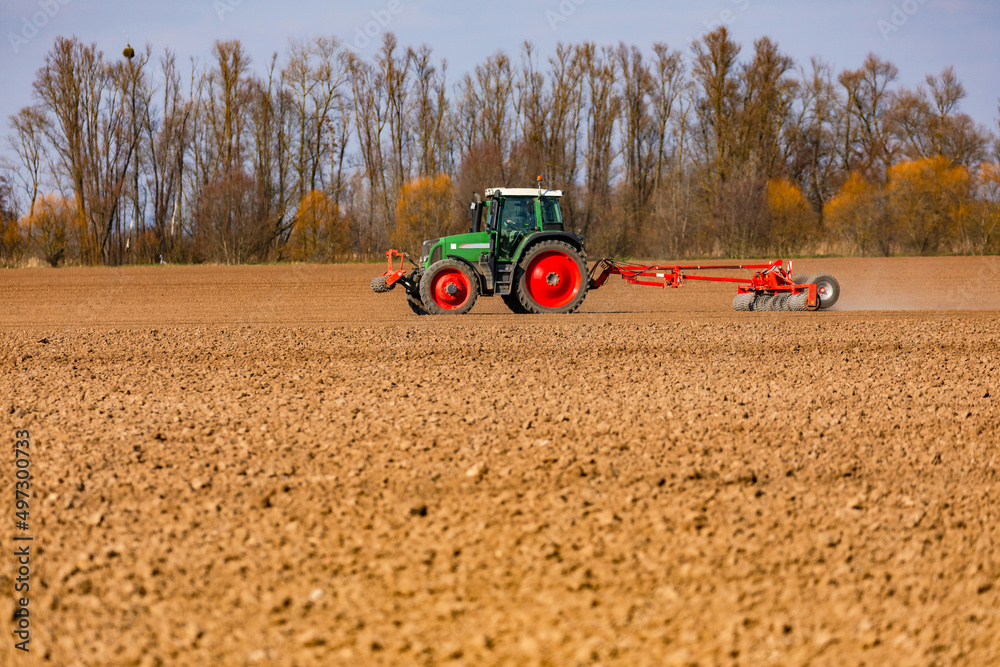 Obraz premium Rural idyll with a tractor plowing a dry field with a plow in the sun in winter