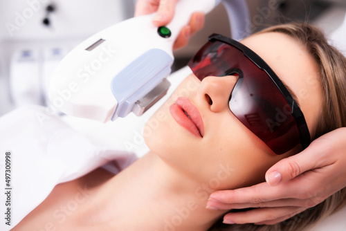 Laser hair removal on a woman\'s face in a beauty salon. Photo of a woman receiving a cosmetologist procedure for skin rejuvenation. The concept of aesthetic medicine. Modern technologies in medicine.