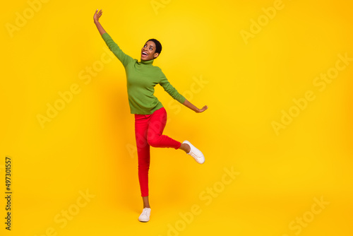 Photo of pretty sweet trans woman wear green turtleneck dancing empty space isolated yellow color background © deagreez