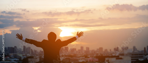 silhouette hand raised fist business man with sun lighting in morning. background city, success, grow up.