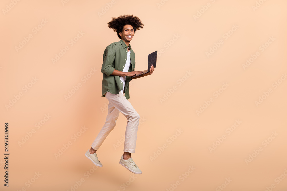 Full size profile portrait of handsome guy use netbook email social network isolated on beige color background Full size profile portrait of handsome guy use netbook email social network isolated on beige color background