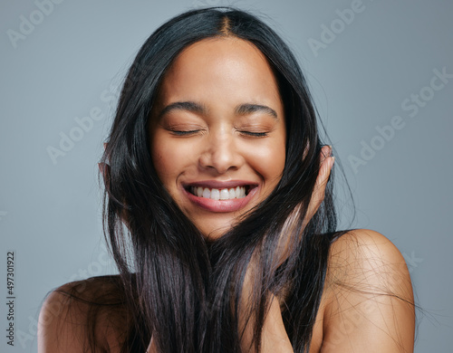 I always give my hair all the nutrients it needs. Studio shot of an attractive young woman posing against a grey background.