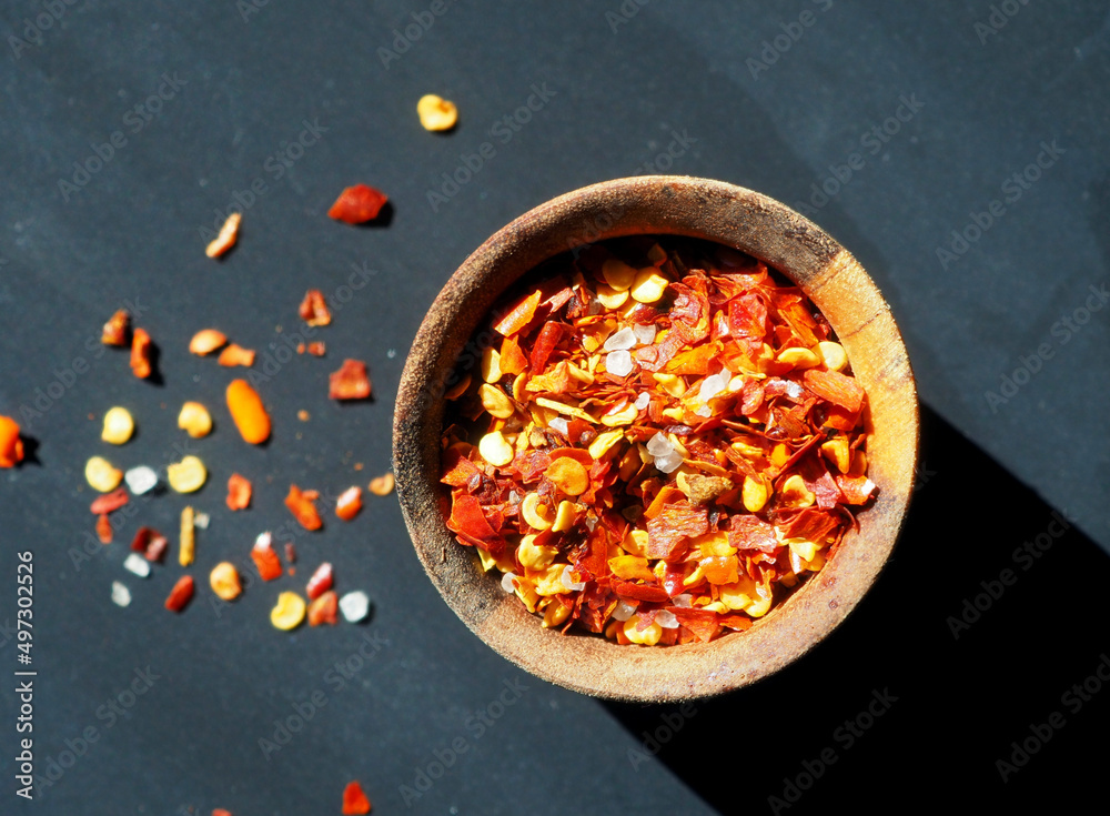 Wooden bowl with spices on a black background. Cayenne, red pepper, sea salt. flat lay