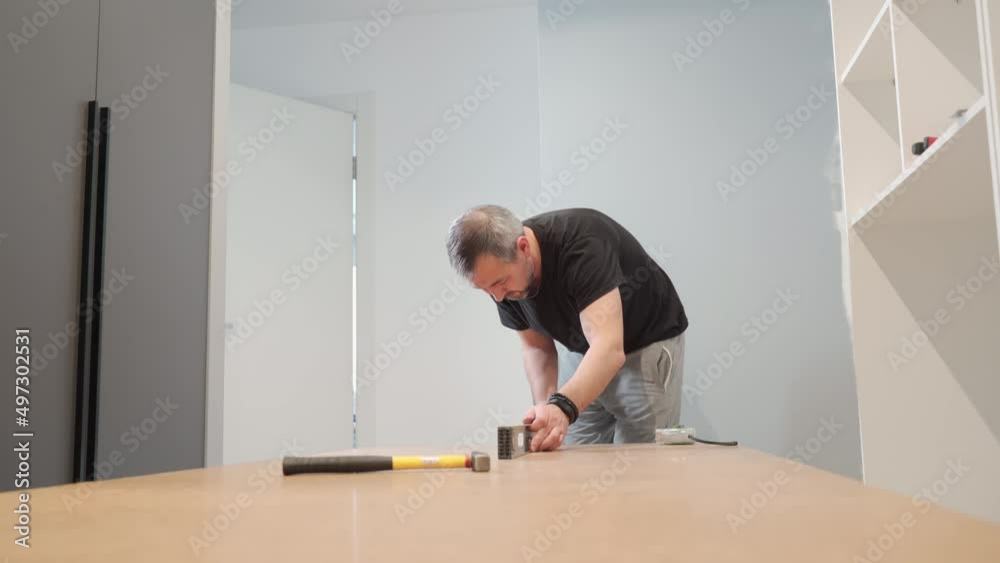 A man hammers nails into the back of a closet. Cabinet assembly. A man hammers nails into the back of a closet. Cabinet assembly.