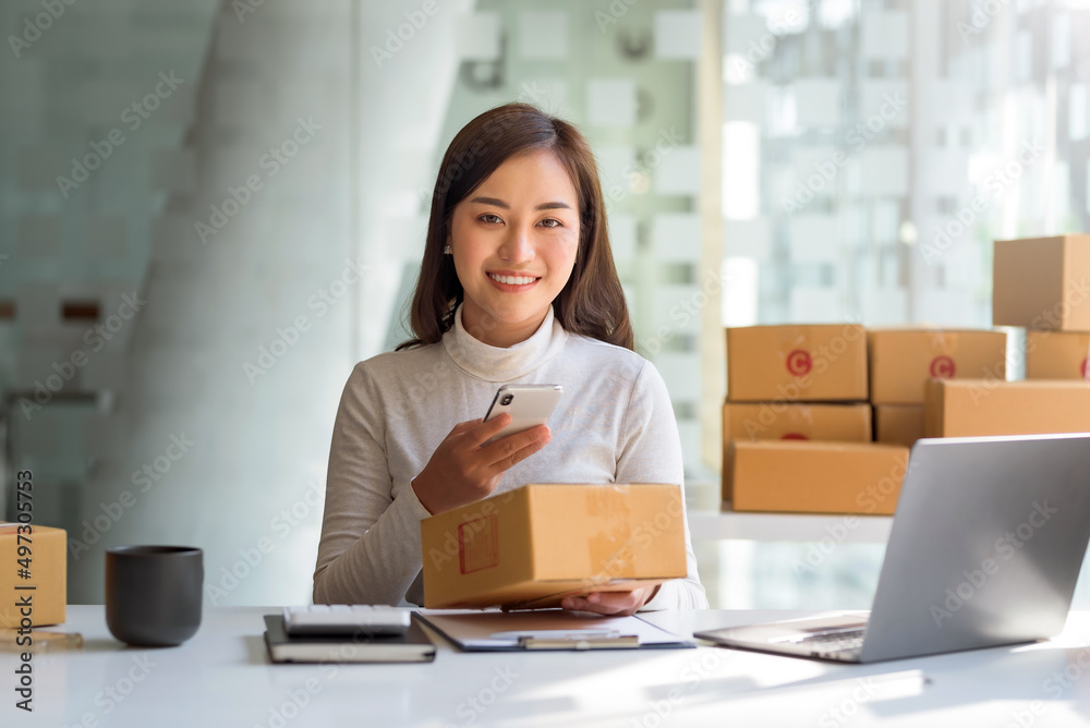 Young Asian small business owner woman hold pen and parcel boxes to write down addresses for delivery to their customers' homes. Looking at camera. Young Asian small business owner woman hold pen and parcel boxes to write down addresses for delivery to their customers' homes. Looking at camera.