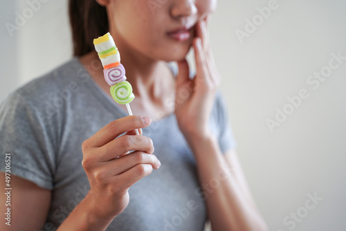 Woman having toothache after eating too much colorful sweets candy lollipop sugar and teeth decay problem photo