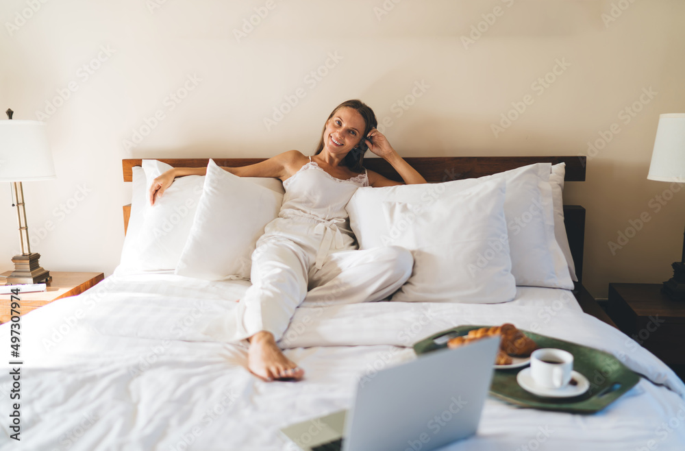 Portrait of happy Caucasian blogger with laptop technology smiling at camera during leisure time in hotel bedroom, cheerful female freelancer with digital netbook technology enjoying room service Portrait of happy Caucasian blogger with laptop technology smiling at camera during leisure time in hotel bedroom, cheerful female freelancer with digital netbook technology enjoying room service