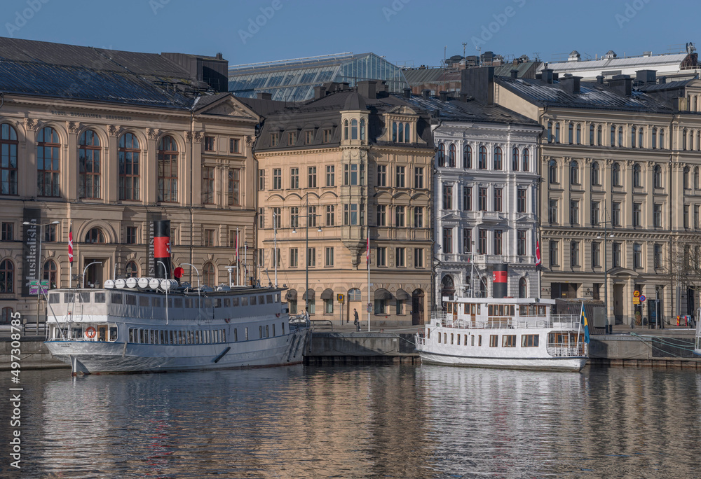 Old steam commuting boats at a pier in the bay Nybroviken a sunny spring day in Stockholm