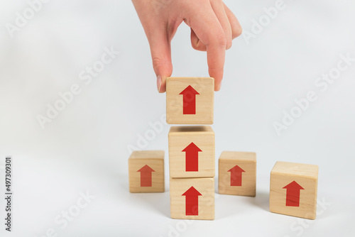 Hand arranging wooden stacking block with up arrow.