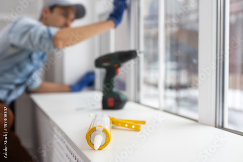 Silicone glue gun, Construction worker installing window in house. Handyman fixing the window with screwdriver photo