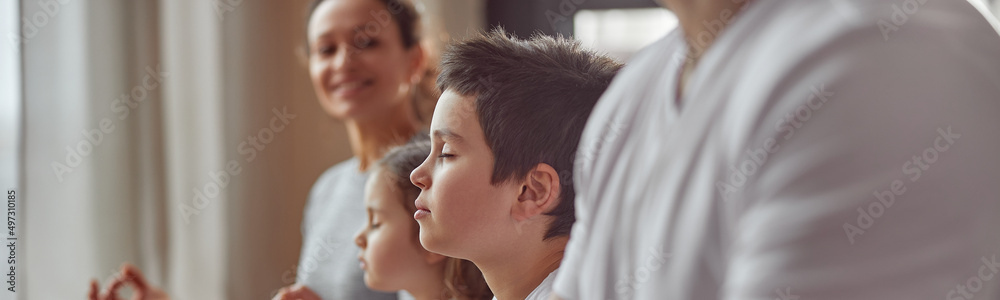 Cropped head of smiling woman watching her husband and kids doing mental practice at home together Cropped head of smiling woman watching her husband and kids doing mental practice at home together