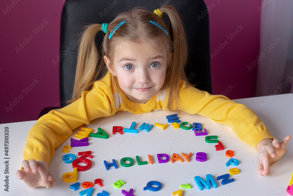 the concept of holidays, the child has English letters laid out on the table, the word holidays is written, waiting for a break from studying the concept of holidays, the child has English letters laid out on the table, the word holidays is written, waiting for a break from studying