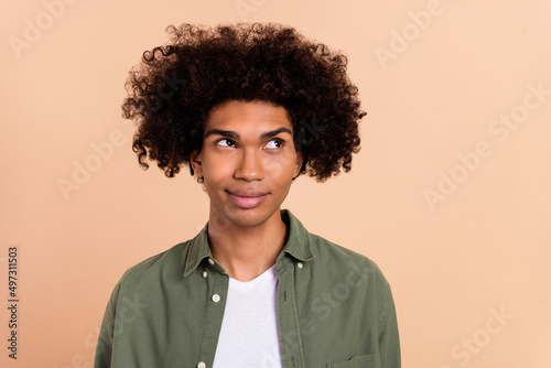 Portrait of attractive minded cheery wavy-haired guy creating solution isolated over beige pastel color background