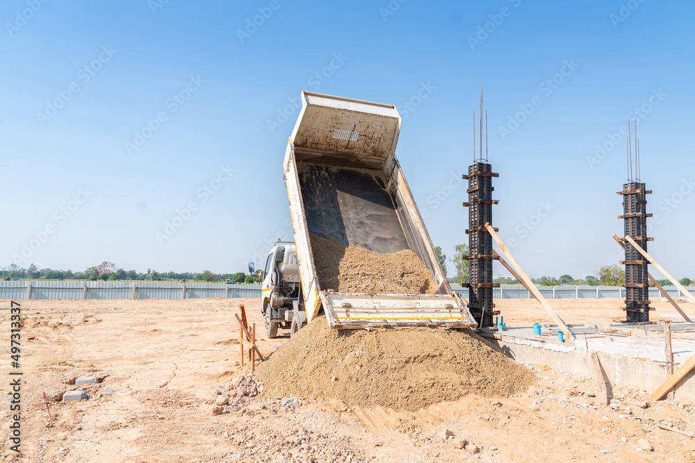 A truck pours sand onto a construction site.