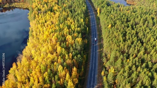Aerial view of the beautiful autumn landscape in sunny day. Forest and calm tranquil lake. White clouds mirroring on water surface.	