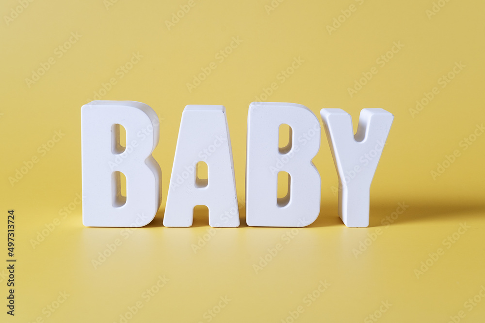 Word baby made from white concrete letters on the yellow background Word baby made from white concrete letters on the yellow background