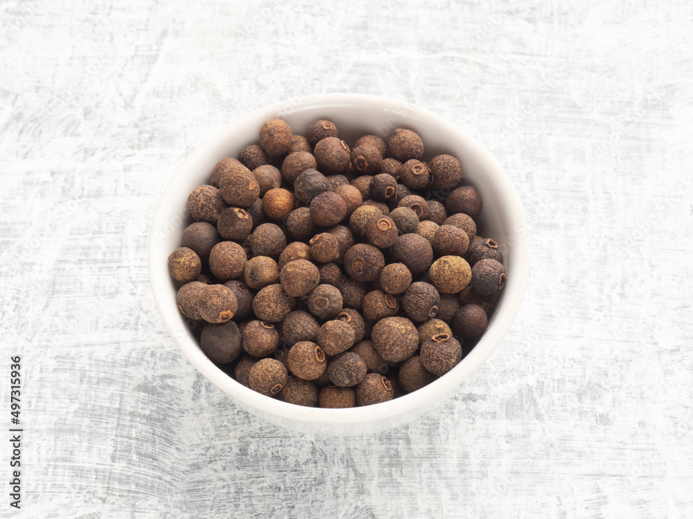 Spice Allspice in white ceramic bowl on white concrete background. Macro. Healthy diet concept Spice Allspice in white ceramic bowl on white concrete background. Macro. Healthy diet concept