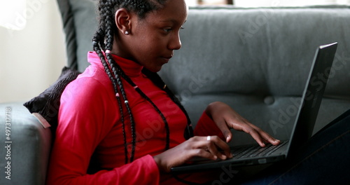 Fotografie African adolescent girl doing homework in front of laptop screen