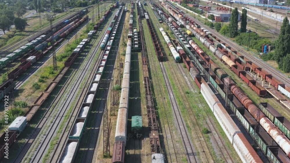 Aerial shot of freight wagons and export container trains on industrial railway terminal. Flying above cargo carriages at railroad station. Transportation or delivery concept. Shipping goods. Top view Aerial shot of freight wagons and export container trains on industrial railway terminal. Flying above cargo carriages at railroad station. Transportation or delivery concept. Shipping goods. Top view