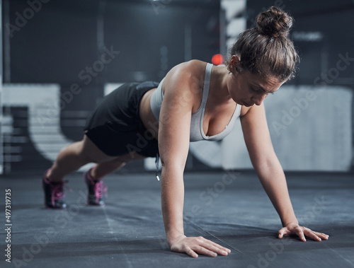 Youre only as strong as you push yourself to be. Shot of a young woman doing push ups at a gym.