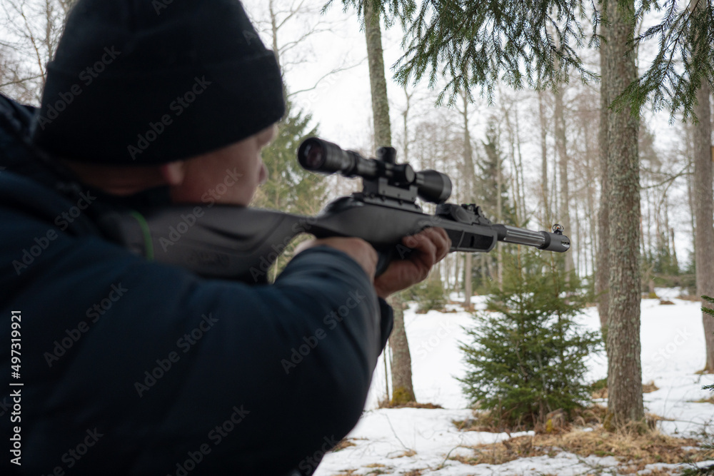 A man with a rifle in the spring forest, the hunter holds a rifle and waits for prey, the hunter shoots A man with a rifle in the spring forest, the hunter holds a rifle and waits for prey, the hunter shoots