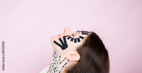 Photos Portrait of woman with colorful tapes on face and neck on pink surface
