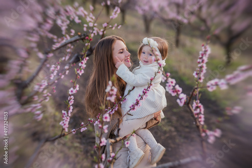 Mother and little daughter are having fun in the blooming rose gardens. Portrait woman hugging girl © farmuty