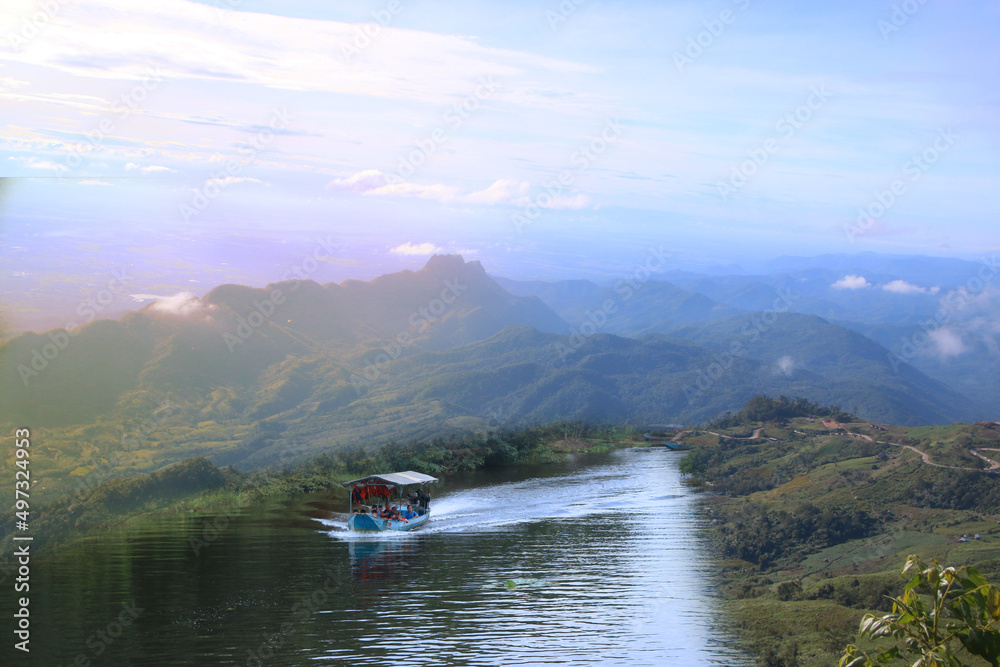 Fototapeta premium River surrounded by trees leading into lake with mountain in background