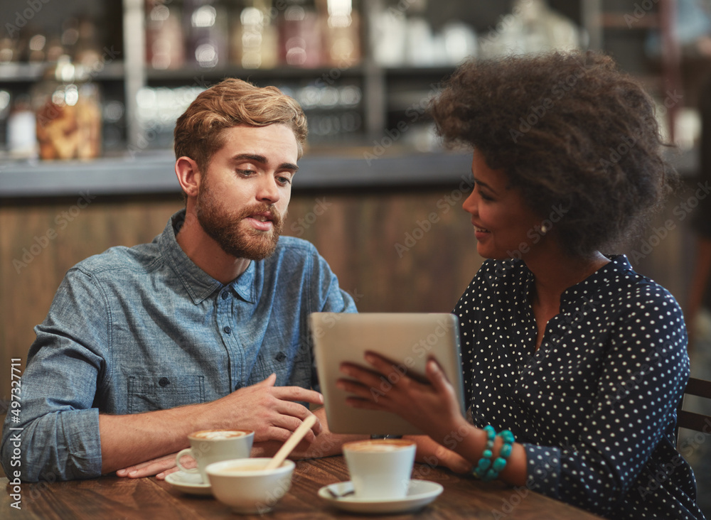 Discussing new ideas for their coffee shop. Shot of a young couple using a digital tablet together on a coffee date.