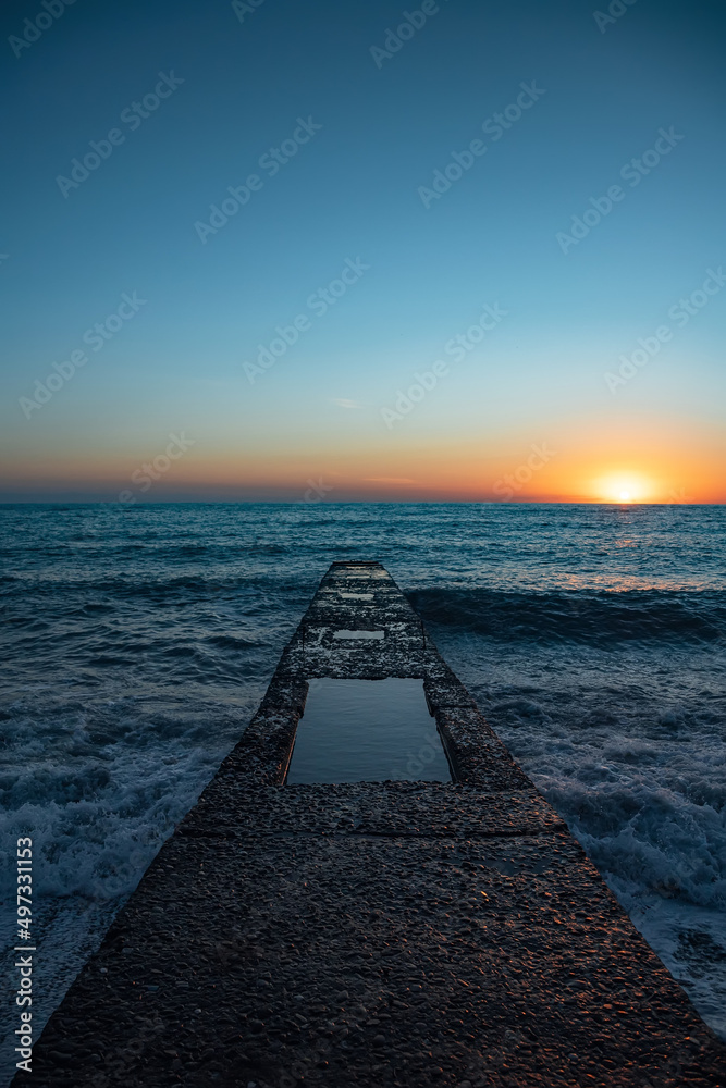 The coastline. Sea sunset. The Black Sea. Concrete pier. Twilight.