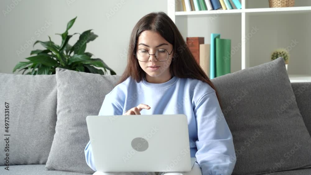 Teen schoolgirl wearing glasses distance learning online looking at web camera at virtual remote lesson class by video conference call at home. Distance education concept. 4k footage Teen schoolgirl wearing glasses distance learning online looking at web camera at virtual remote lesson class by video conference call at home. Distance education concept. 4k footage