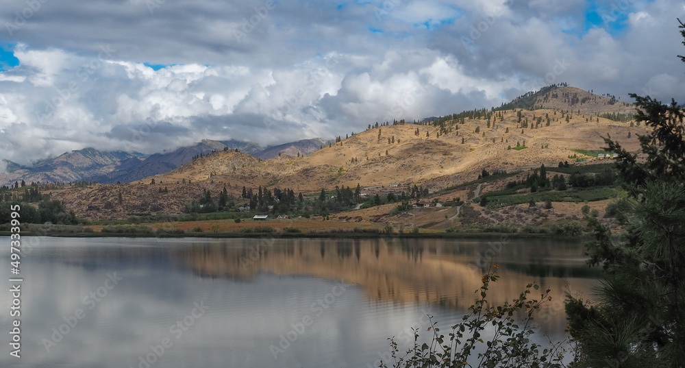 Brown desert mountains surround Wapato Lake which reflects the beautiful cloudy skies near Manson in Eastern Washington State.