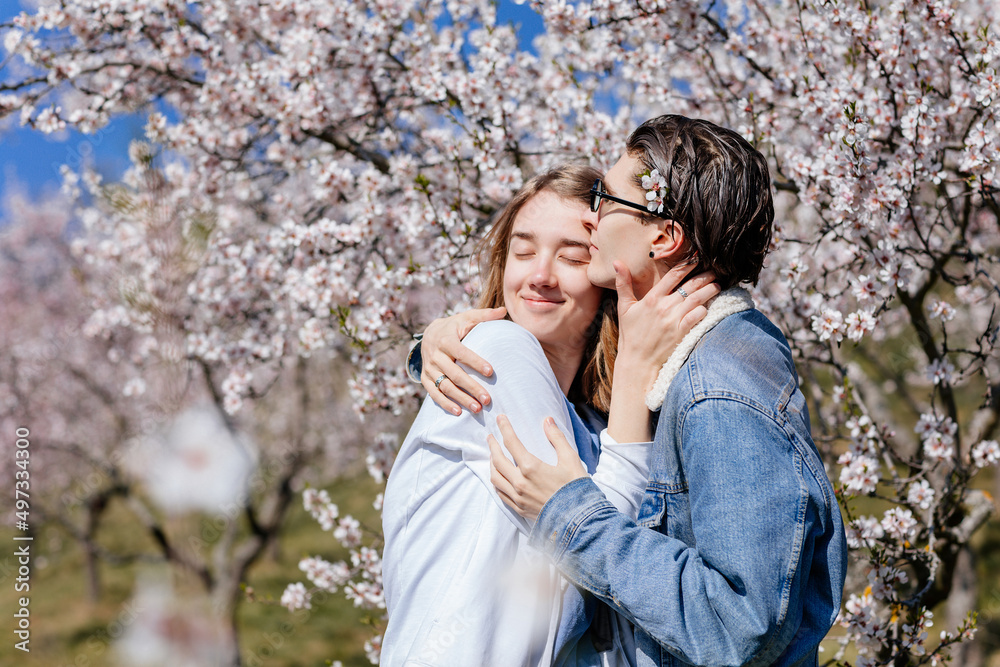 Happy young family lovely couple enjoy walking in spring blooming park, sunny garden on Petrin Hill in Prague, almond and Sakura, close-up portrait, man holds the woman's hand, relationships in love Happy young family lovely couple enjoy walking in spring blooming park, sunny garden on Petrin Hill in Prague, almond and Sakura, close-up portrait, man holds the woman's hand, relationships in love