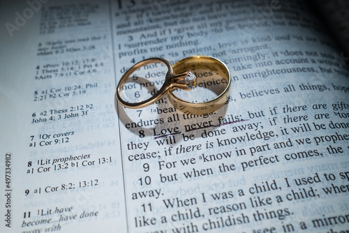 Gold Wedding Rings on a Bible with the Scripture Love Never Fails