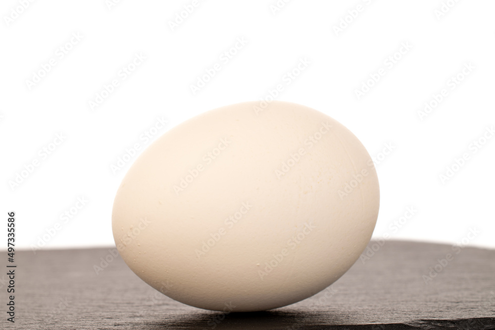 One white chicken egg on a slate stone, macro, isolated on a white background. One white chicken egg on a slate stone, macro, isolated on a white background.