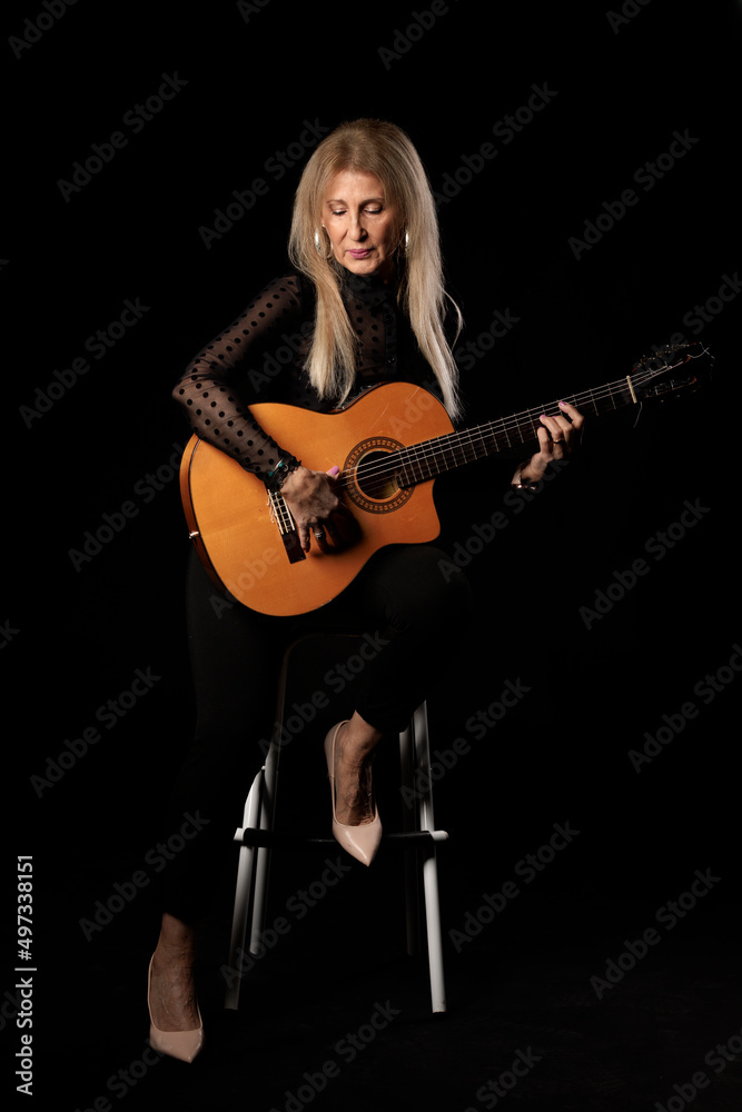 blonde woman with guitar in studio on black background blonde woman with guitar in studio on black background
