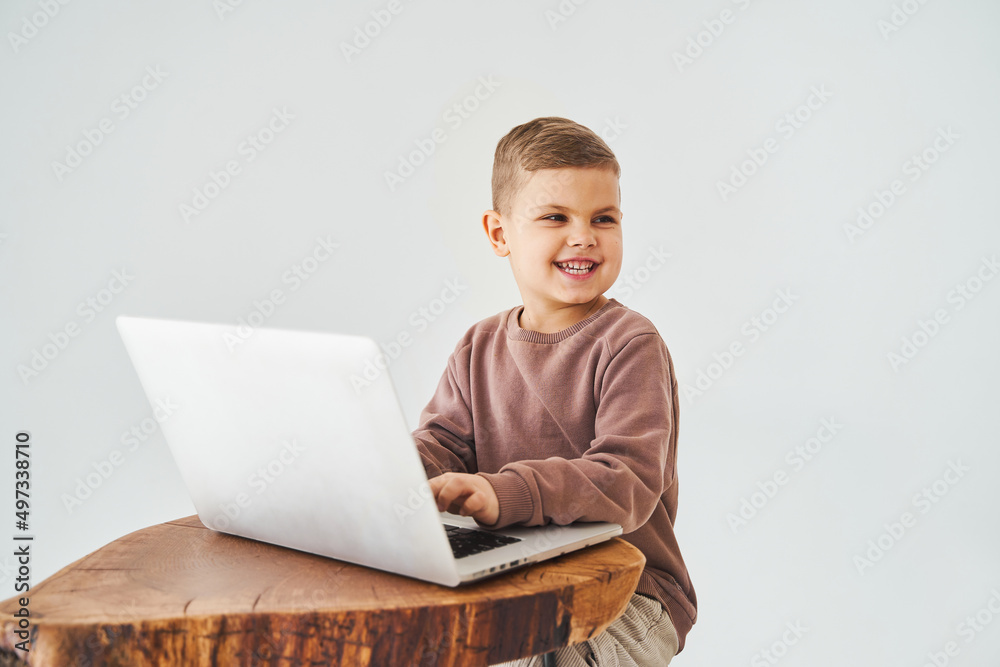 Gambling addiction. Handsome kid gamer is gaming on laptop on white background. Emotional child play online games on laptop. Gambling addiction. Handsome kid gamer is gaming on laptop on white background. Emotional child play online games on laptop.