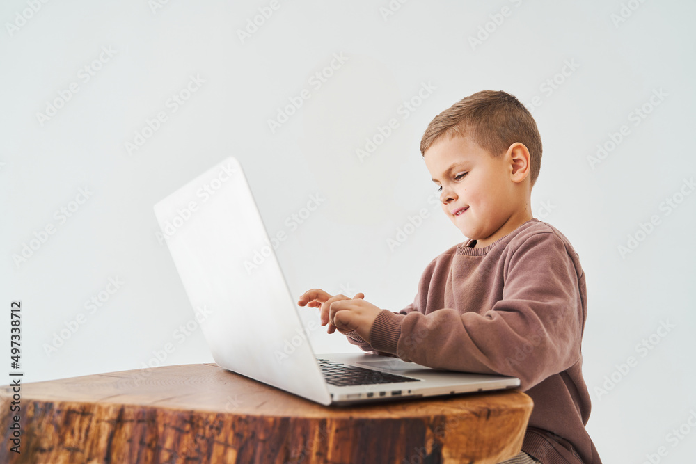 Emotional child with laptop talking with friends online. Handsome kid typing text on laptop and smile. Emotional child with laptop talking with friends online. Handsome kid typing text on laptop and smile.